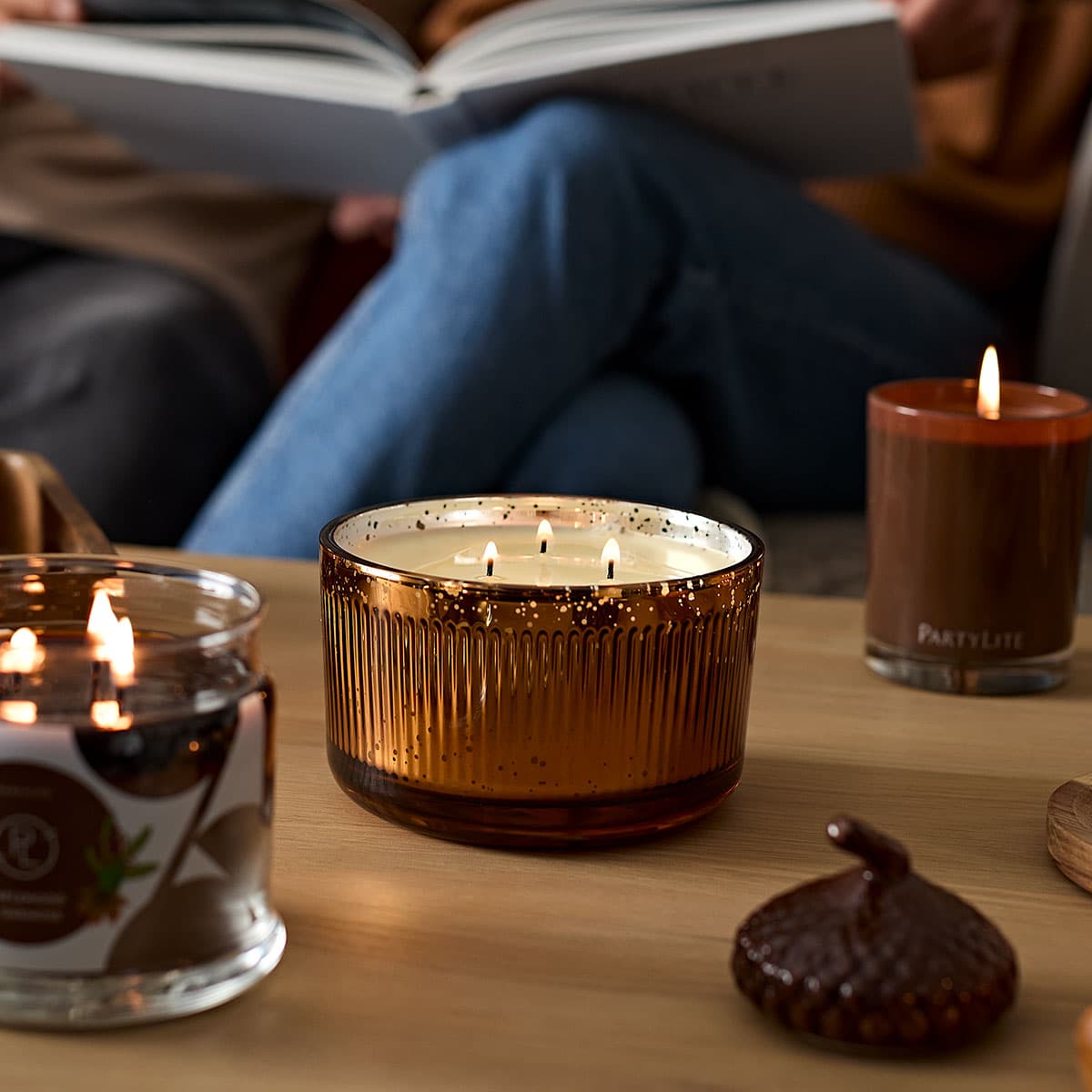 Woodland Pumpkin 3-Wick Ripple Jar Candle shown with the 3-wick Jar candle and the Escential Jar all lit on a wooden table