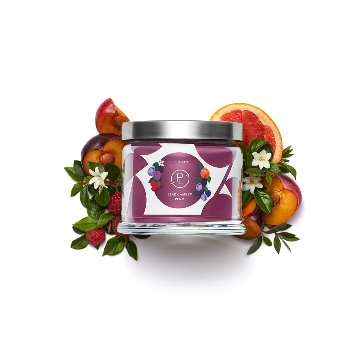 Black Amber Plum 3-Wick Jar Candle surrounded by sliced fruit and leaves against a white background.