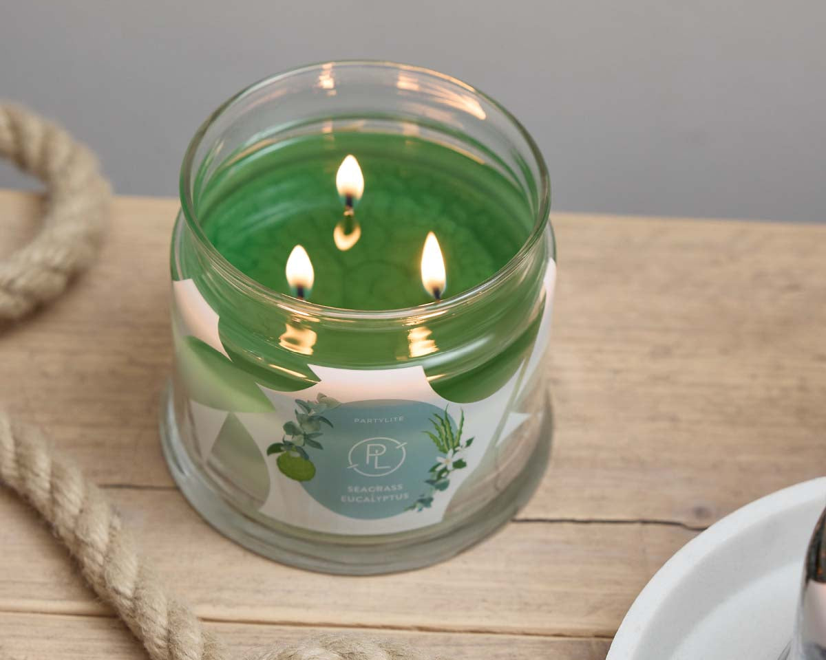 Seagrass Eucalyptus 3-Wick Jar Candle on a wooden surface with a rope lying next to it.