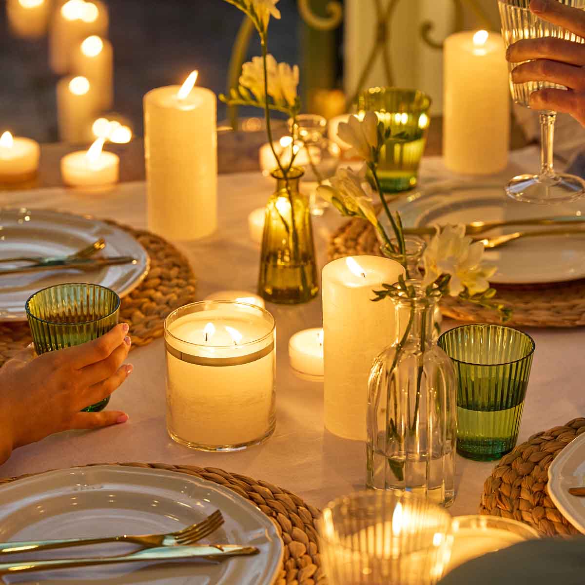 Assortment of GloLite Pillars, Jar and Large Tealights on a table setting, with plates and cutlery.