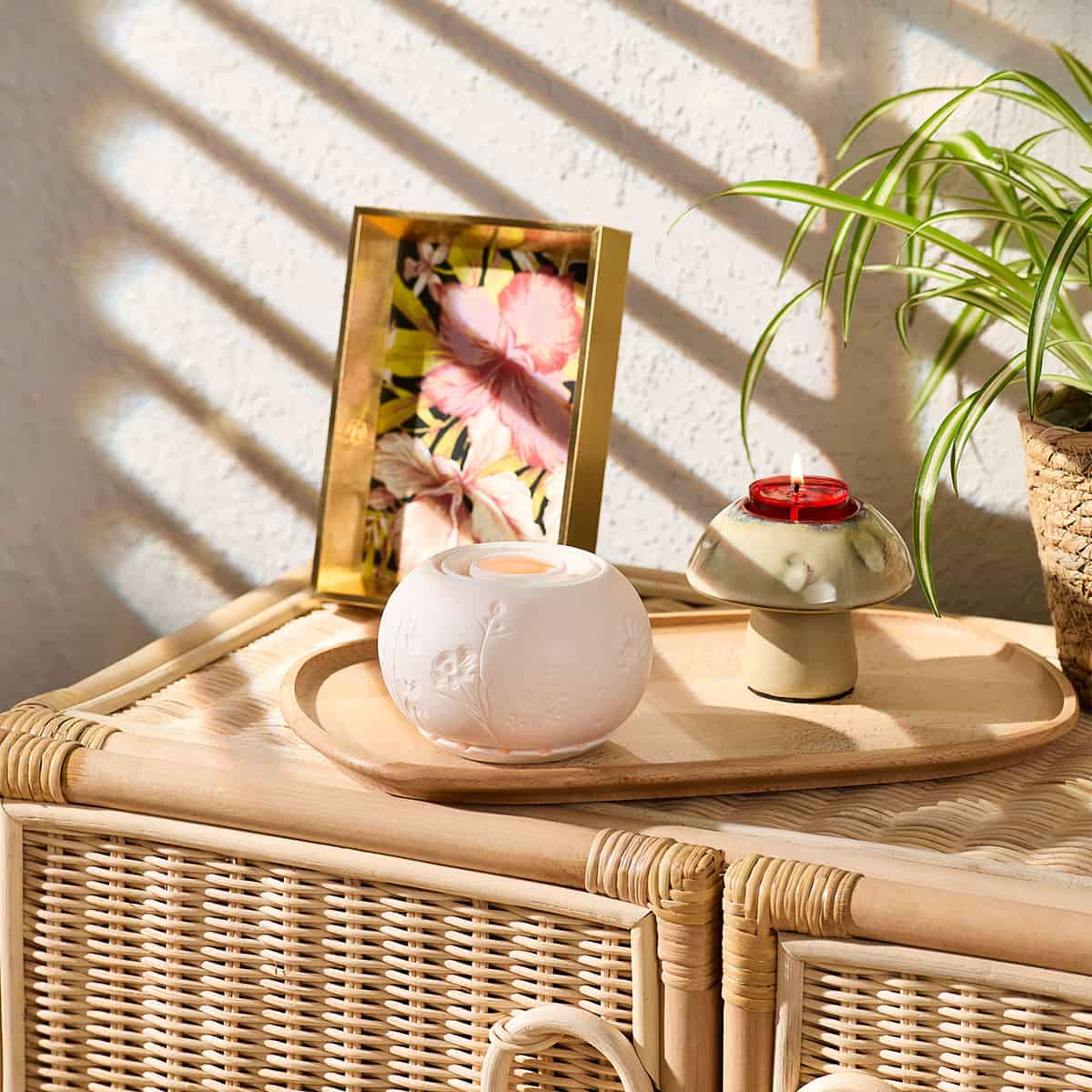 Munchkin Mushroom Tealight Holder shown with the Illuminescents Blooming Fields fragrance warmer, on a wooden tray on a wicker cabinet with a light background